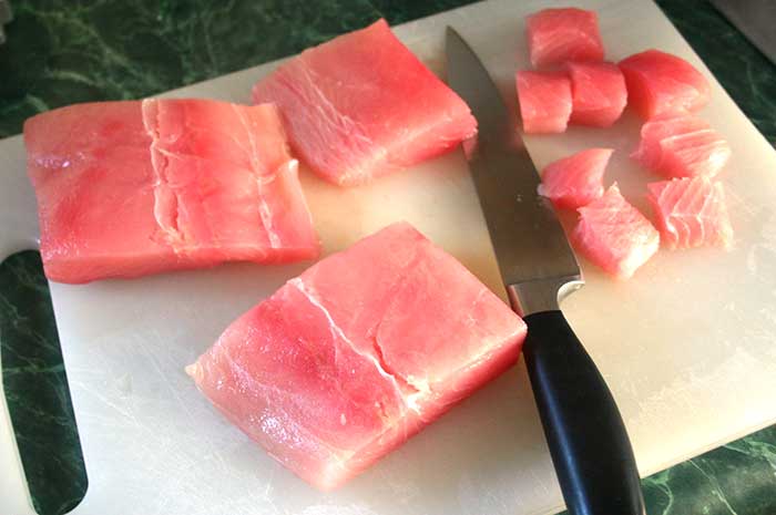 Fresh raw mahi-maji on a cutting board, cut into chunks