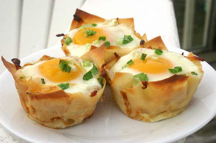 Three Baked Eggs in Wonton Cups garnished with chives on a white plate