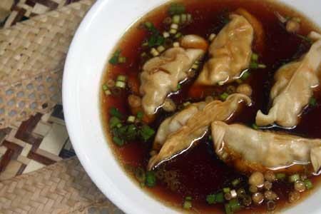 Potsticker Soup in a white bowl with scallions.