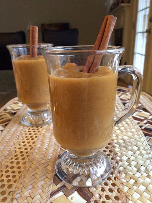 Butternut Squash Soup with Apples and Carrots in two glass mugs garnished with cinnamon sticks