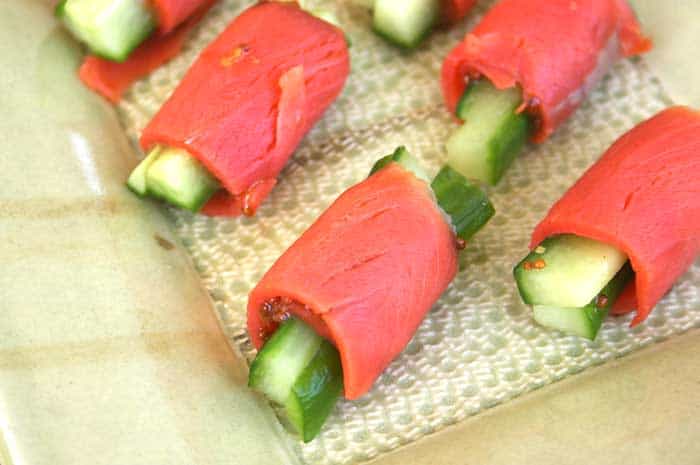 Multiple Smoked Salmon Cucumber Rolls laid out on a serving tray