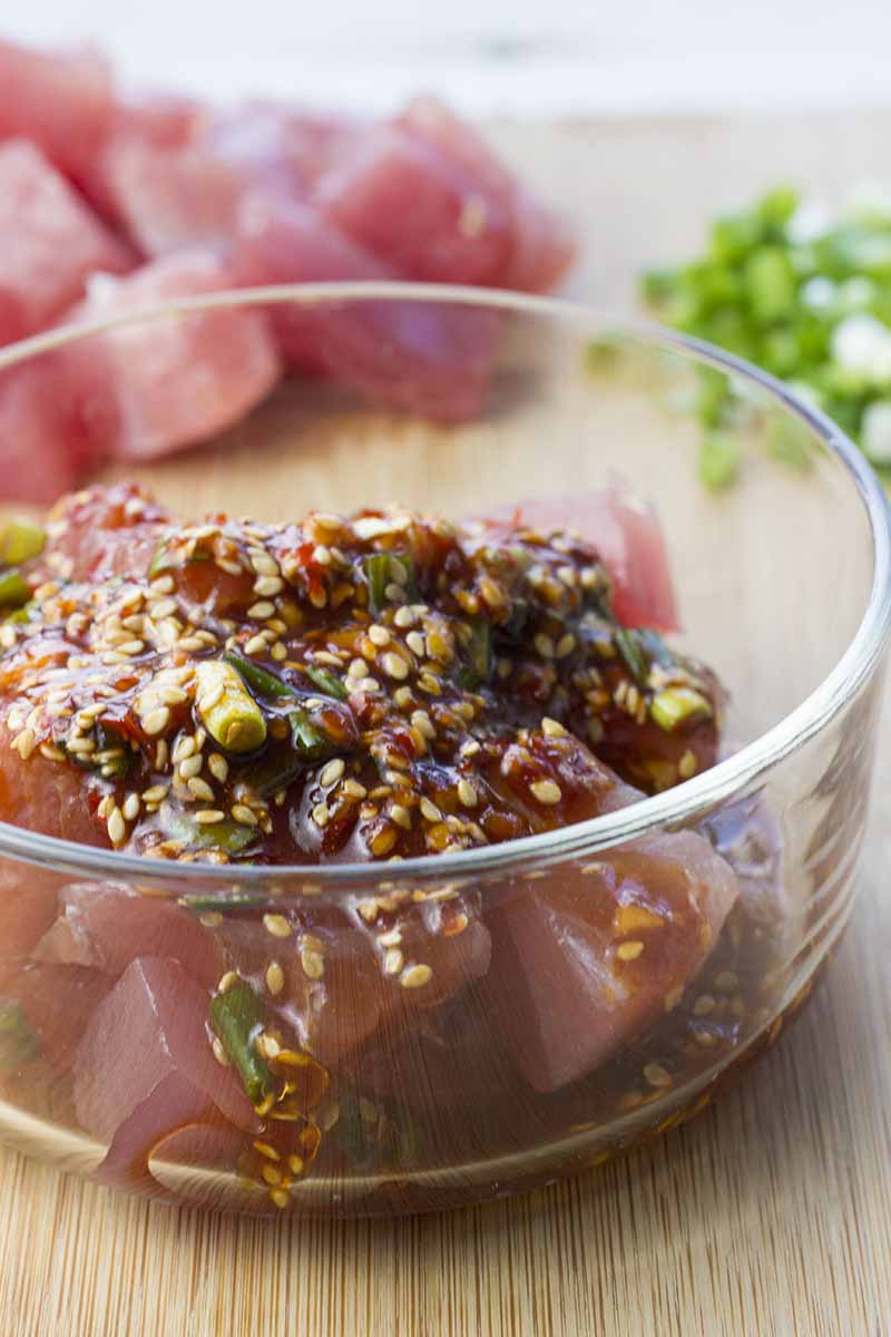 Sesame oil mixture poured over raw ahi tuna in a glass bowl