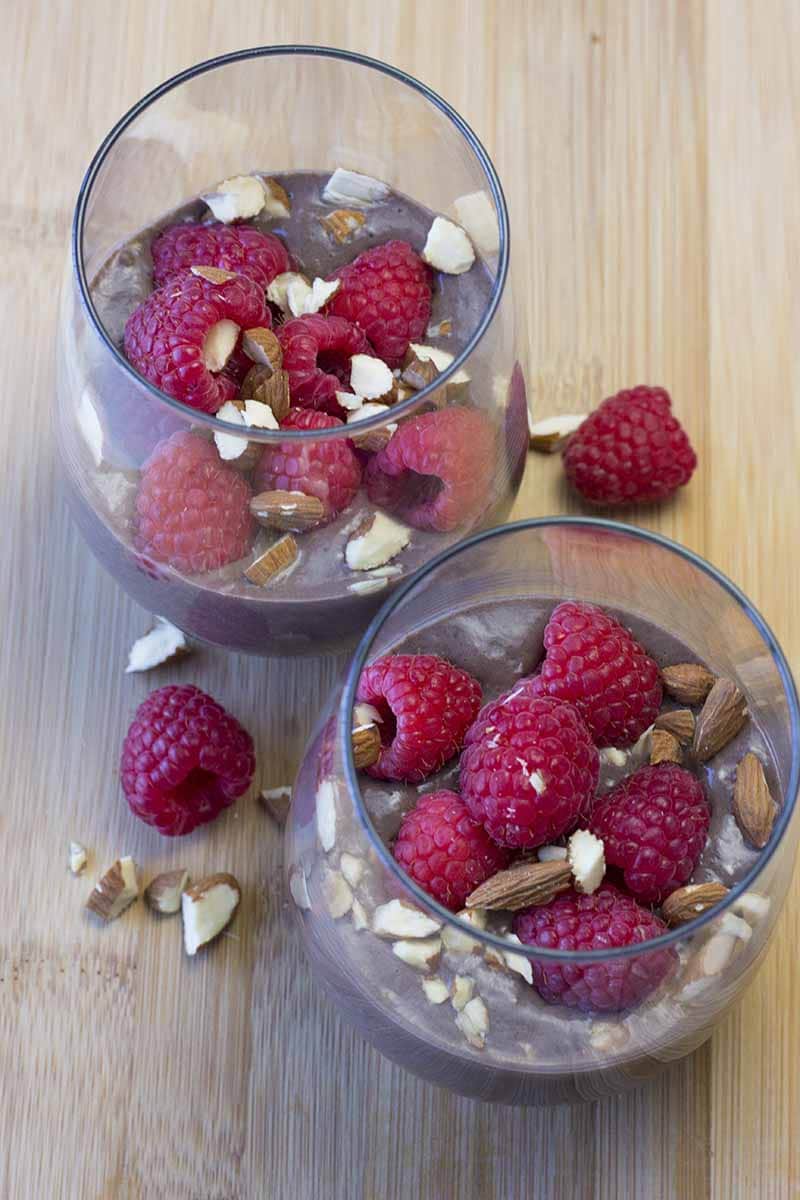 chocolate overnight oats in two glasses, topped with raspberries and chopped almonds