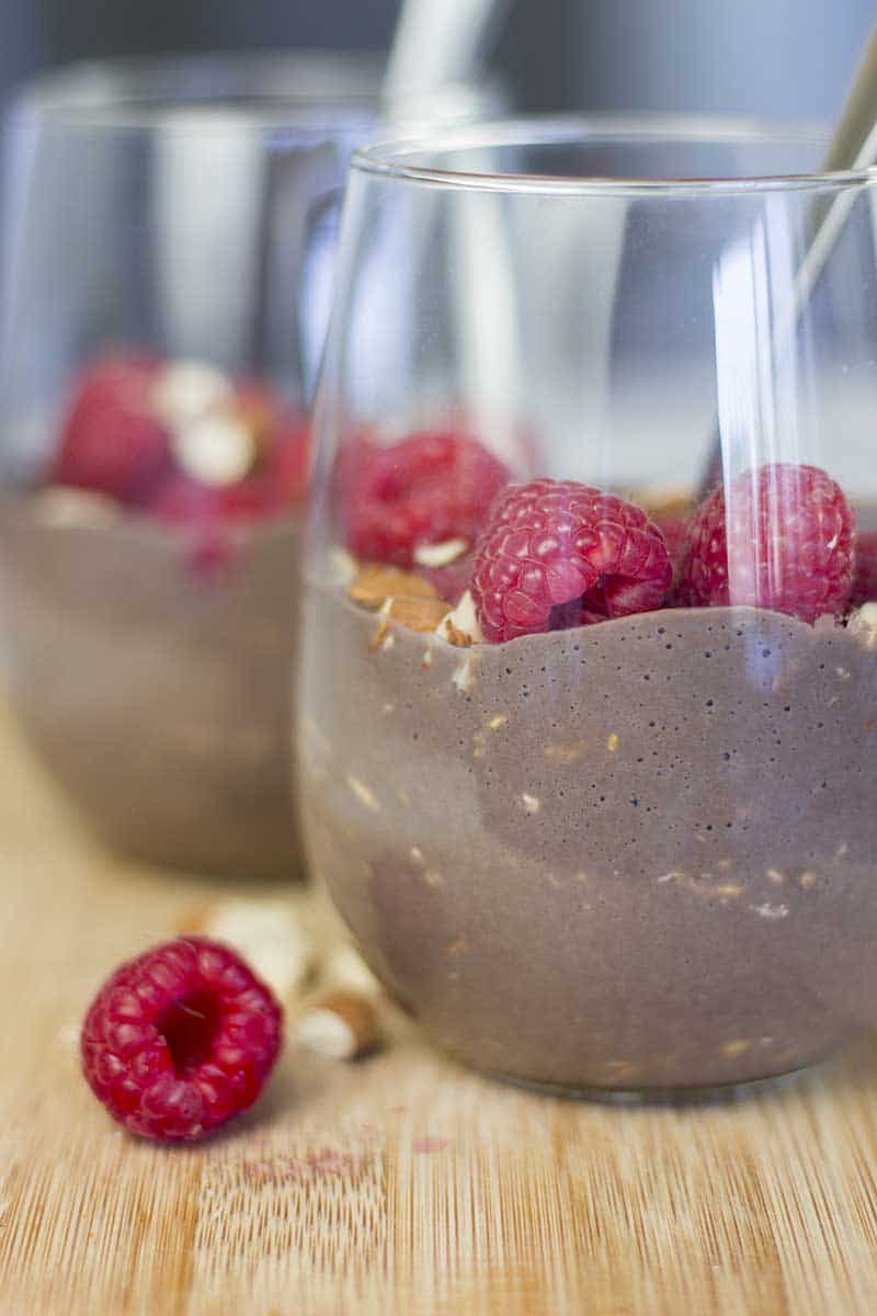 High Protein Chocolate Overnight Oats with Almond Milk in a glass with raspberries and almonds on top