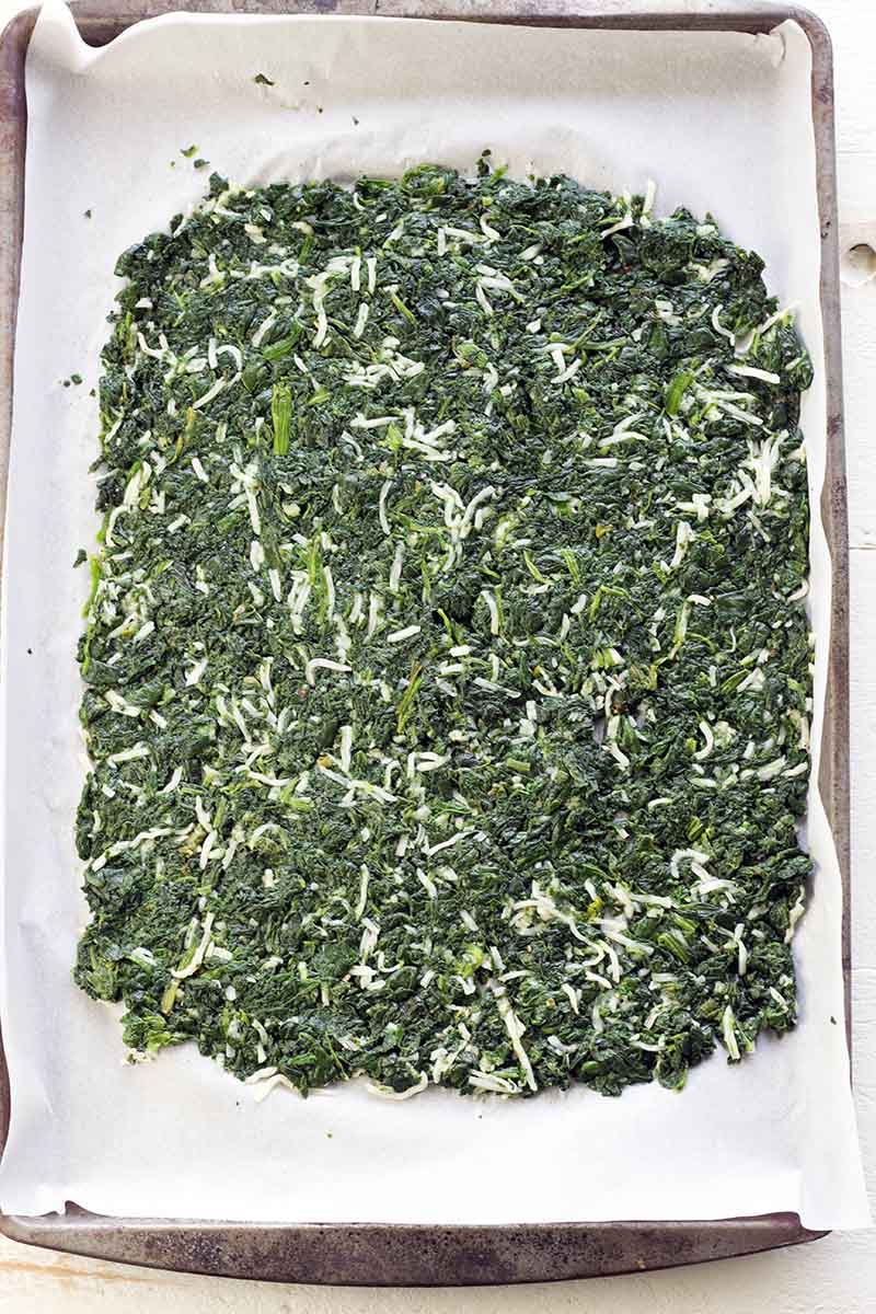 Spinach, eggs, mozzarella, garlic, salt, and pepper mixed together and spread out on a sheet of parchment paper