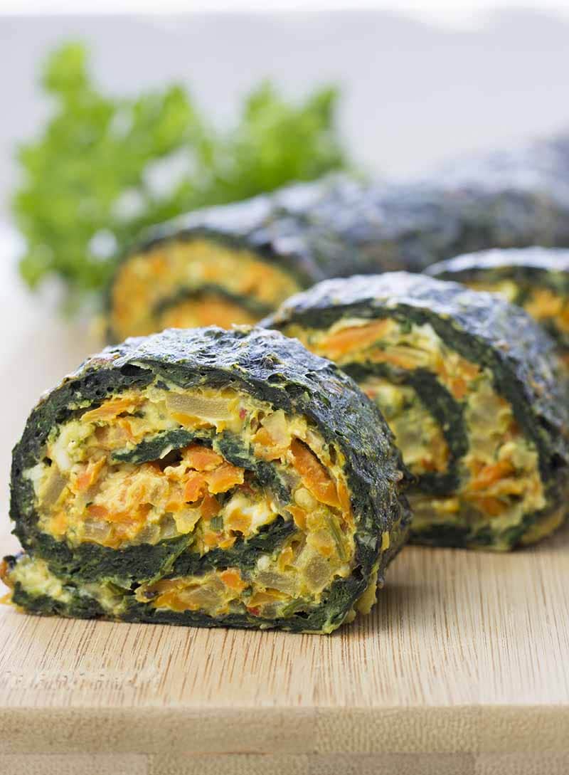 Vegetarian Spinach Rolls cut into slices on a wooden cutting board 