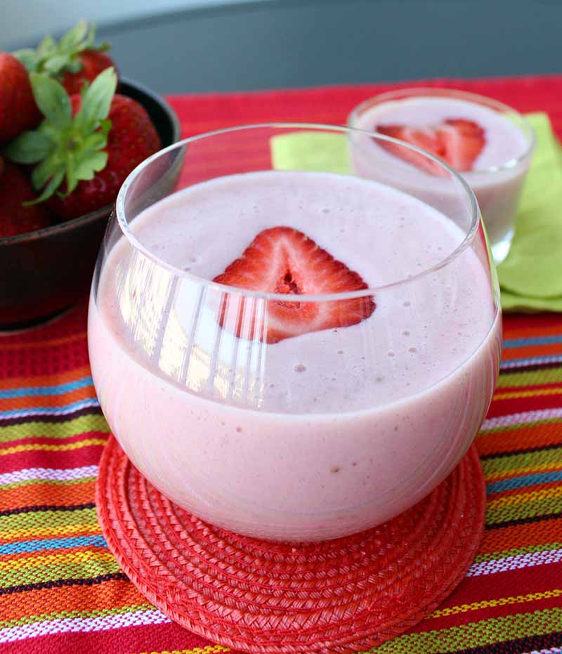 Bicchiere di frullato proteico alla fragola e banana con una fragola affettata in cima