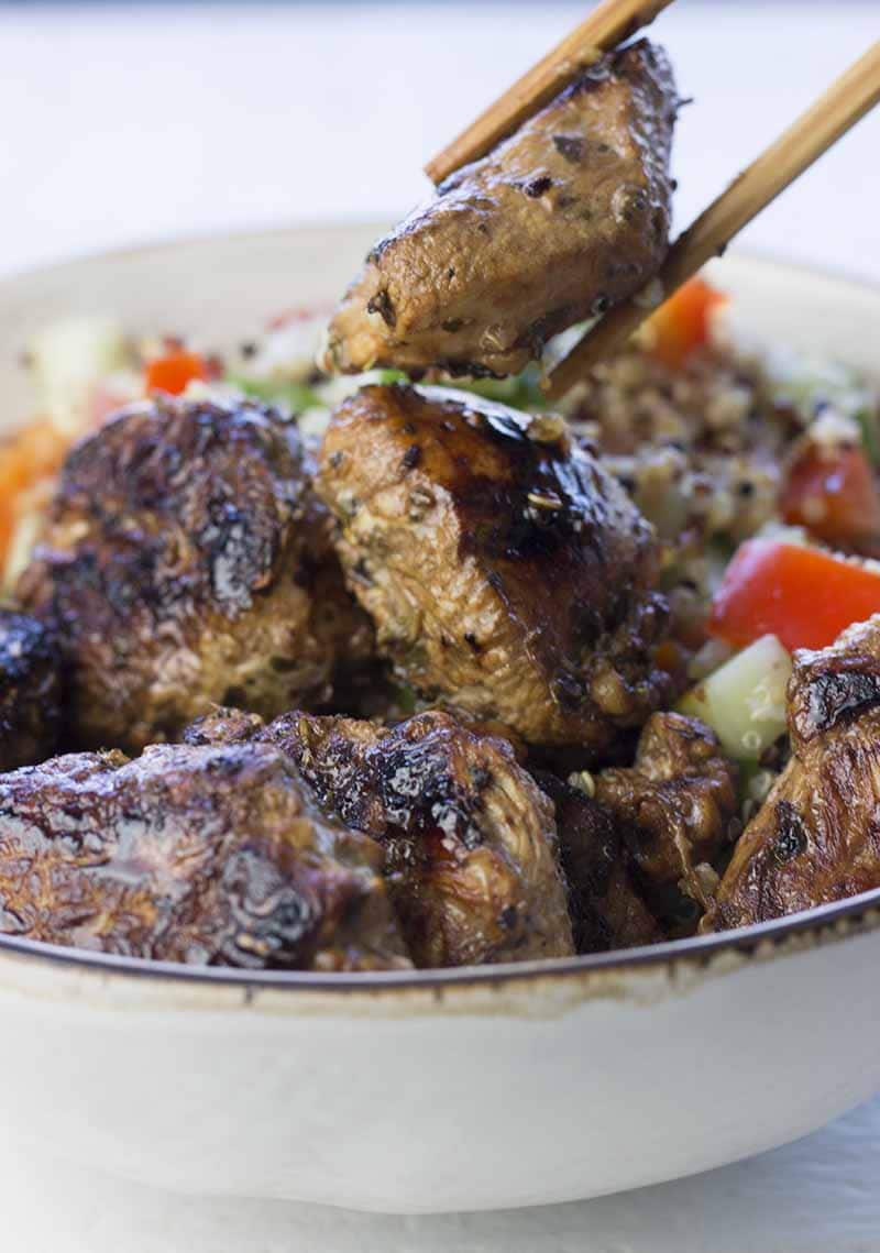 Bowl of marinated turkey breast pieces with chopsticks holding one piece