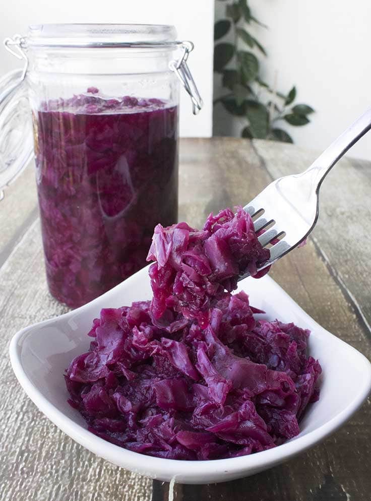 Braised Red cabbage in a small serving dish with a larger portion stored in a jar behind it