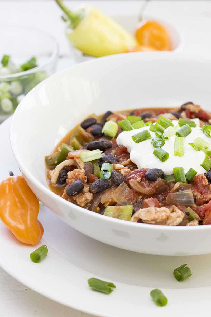 Simple turkey chili in a bowl, topped with sour cream and sliced green onions