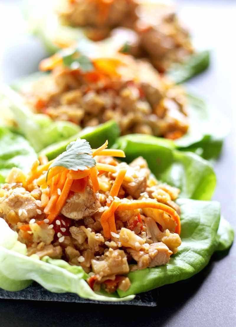 Three Healthy Chicken Lettuce Wraps with shredded carrot and cilantro garnish on a platter