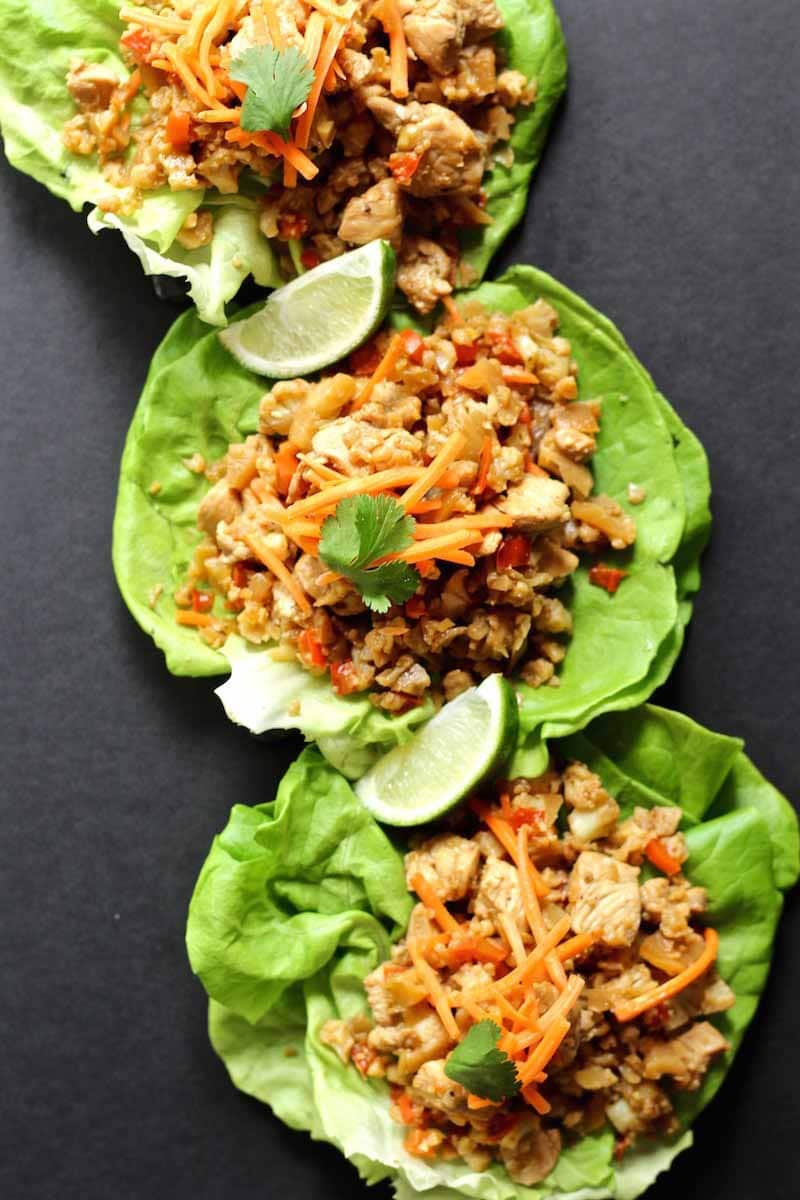 Overhead view of the lettuce wraps with the chicken and vegetable fillings, topped with cilantro and lime wedges