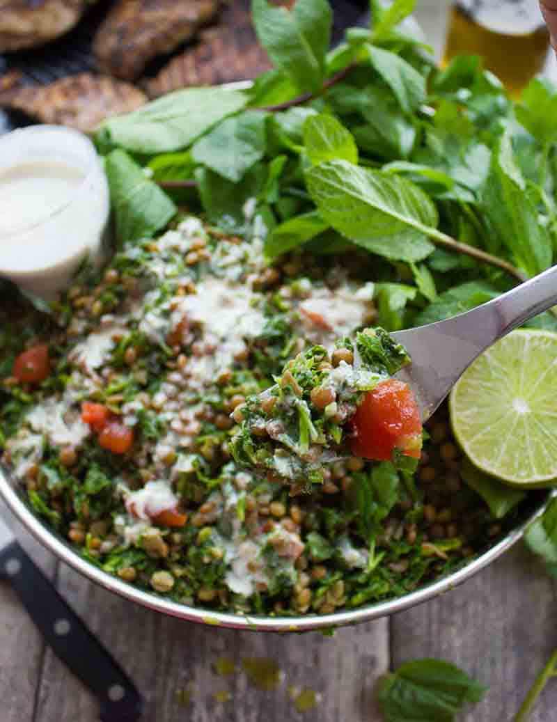 A spoonful of tabbouleh with the full dish in the background