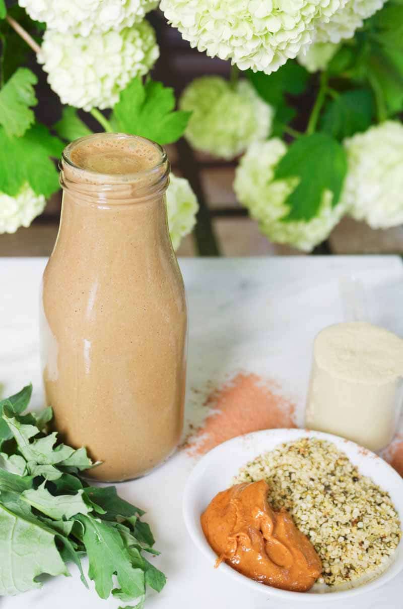 Bottle of Vegan Peanut Butter Protein Smoothie surrounded by all the raw ingredients 