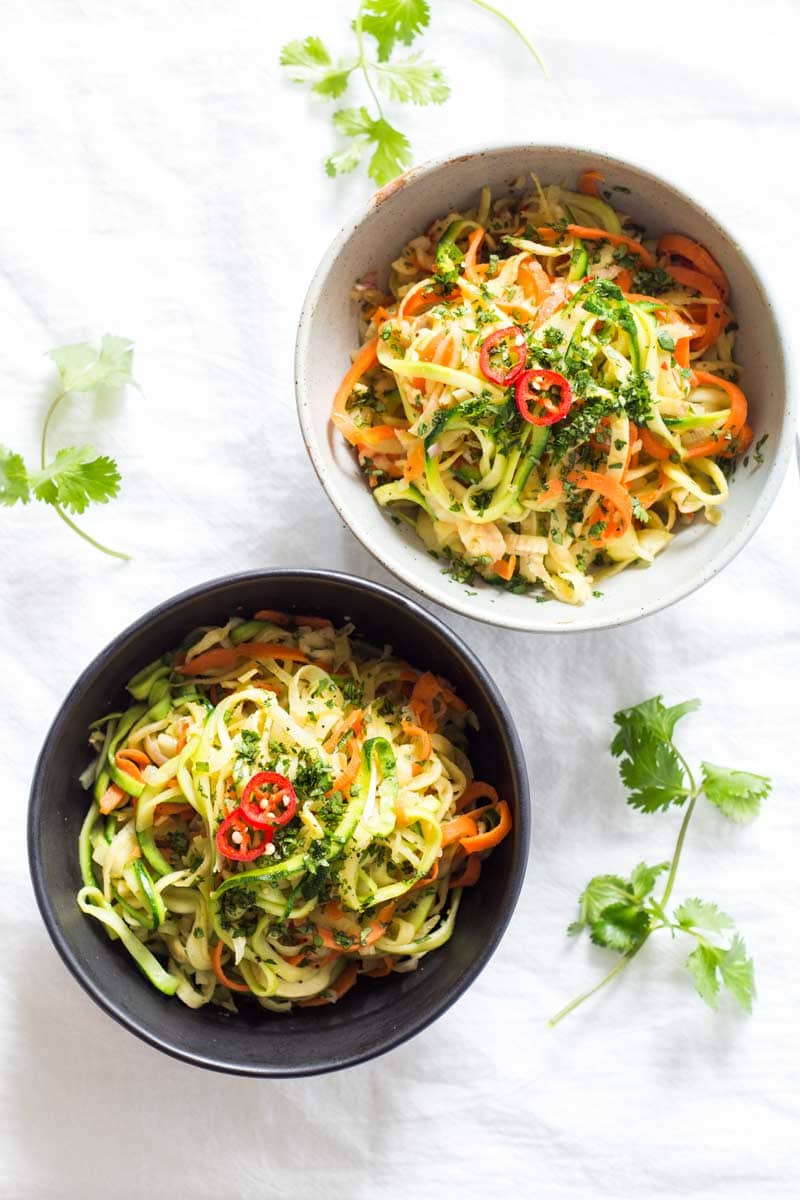 Two bowls of spiralized stir-fried noodles garnished with cilantro and red chili slices, as seen from above