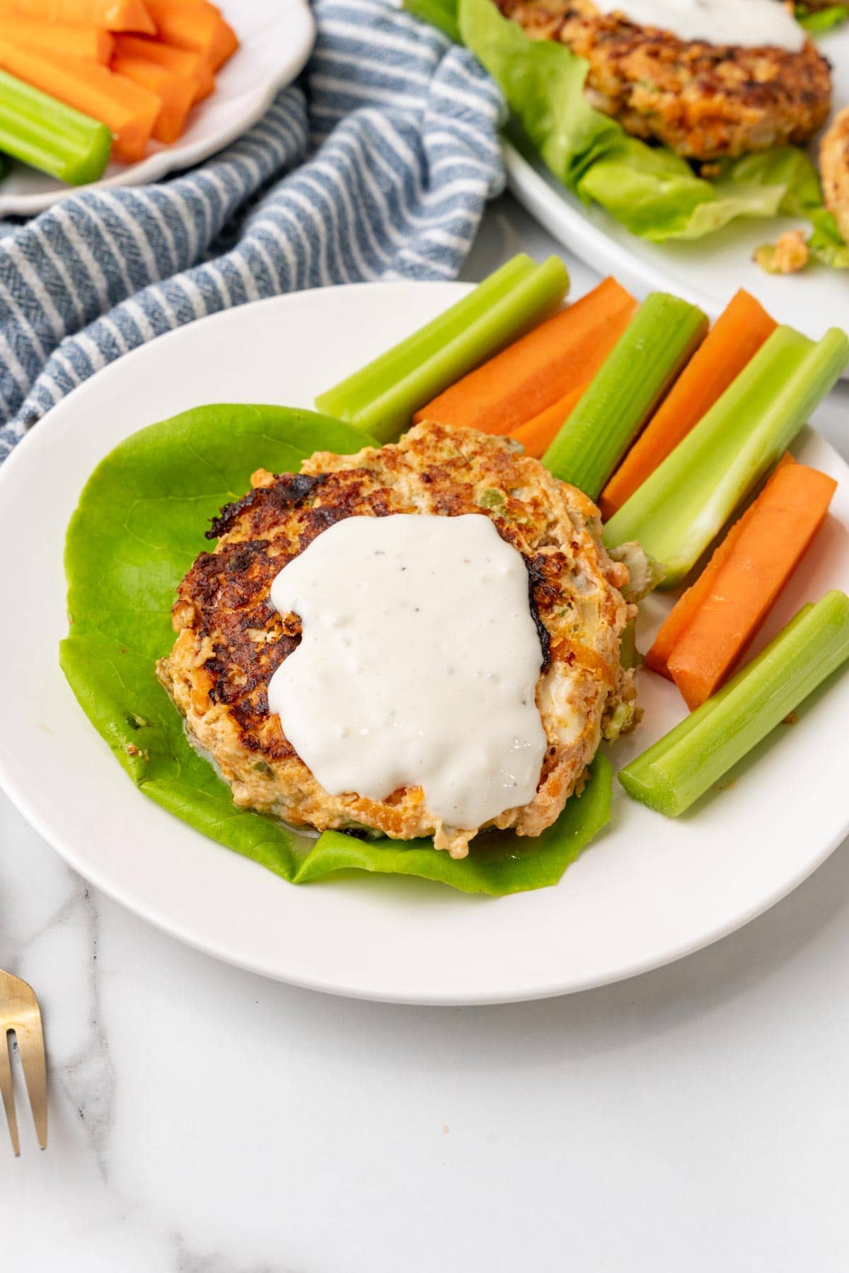 Two buffalo chicken burgers with blue cheese sauce and veggies