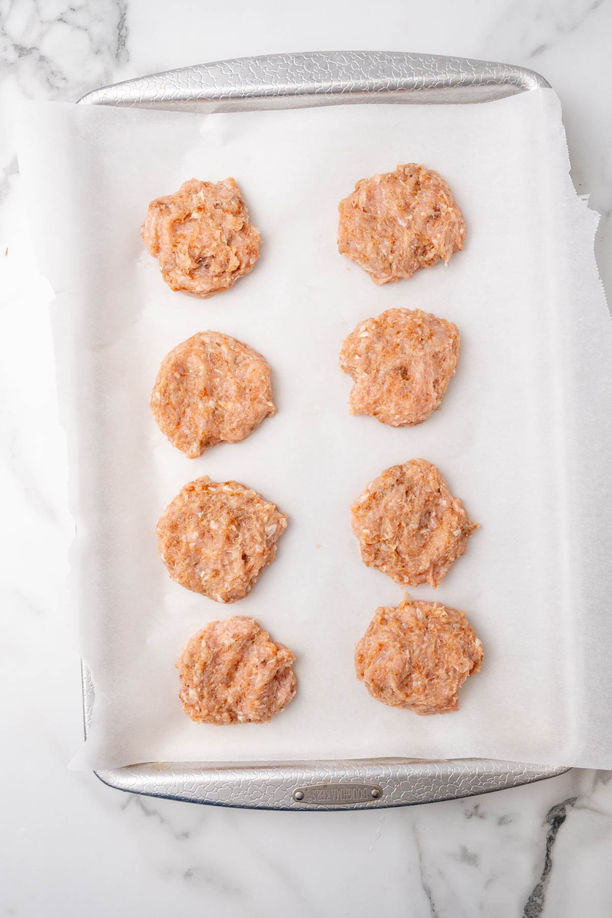 Eight sausage patties on a baking sheet