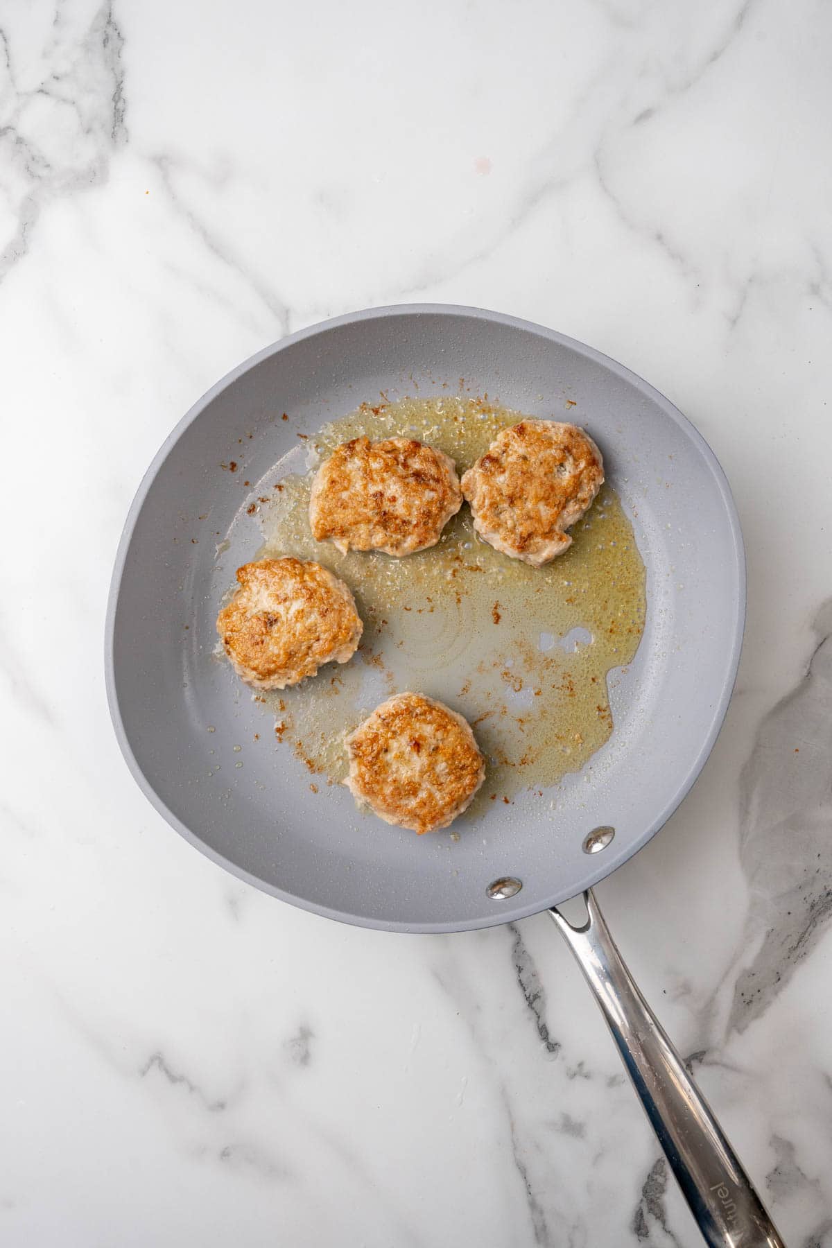 Four low-sodium breakfast sausages coking on a pan