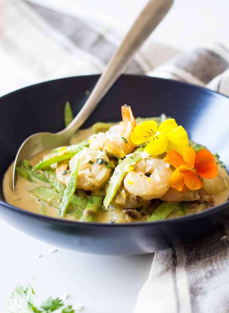 A bowl of green curry topped with shrimp
