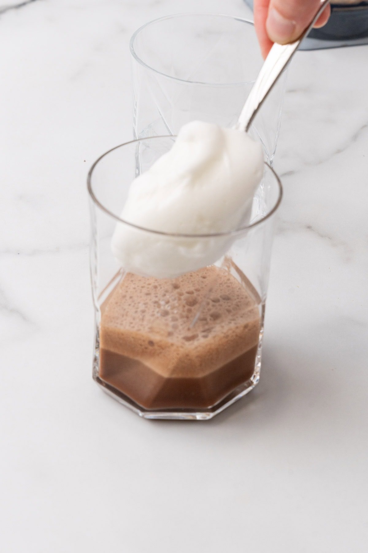 Blended egg whites being added to a glass of chocolate coffee protein shake