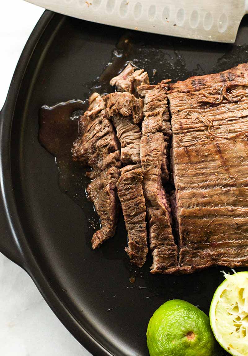 Cooked flank steak being sliced into strips, as seen from above