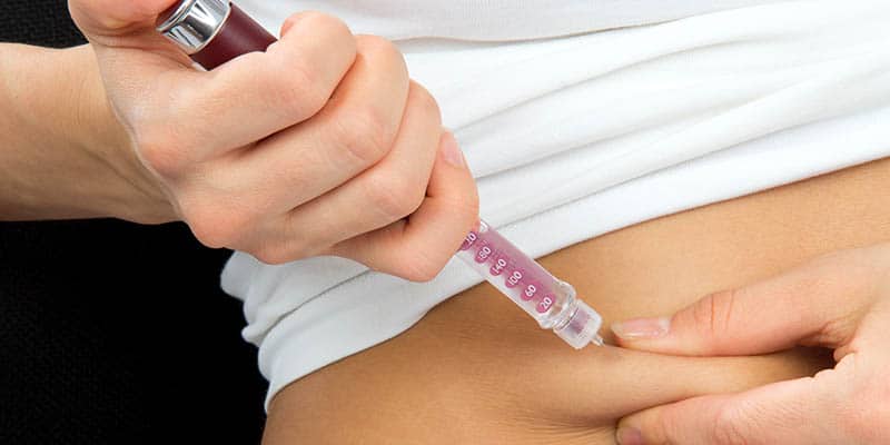 Person injecting insulin into abdomen