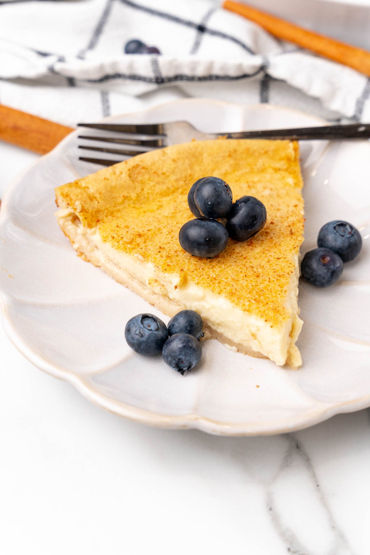 Slice of crustless custard pie on plate with blueberries