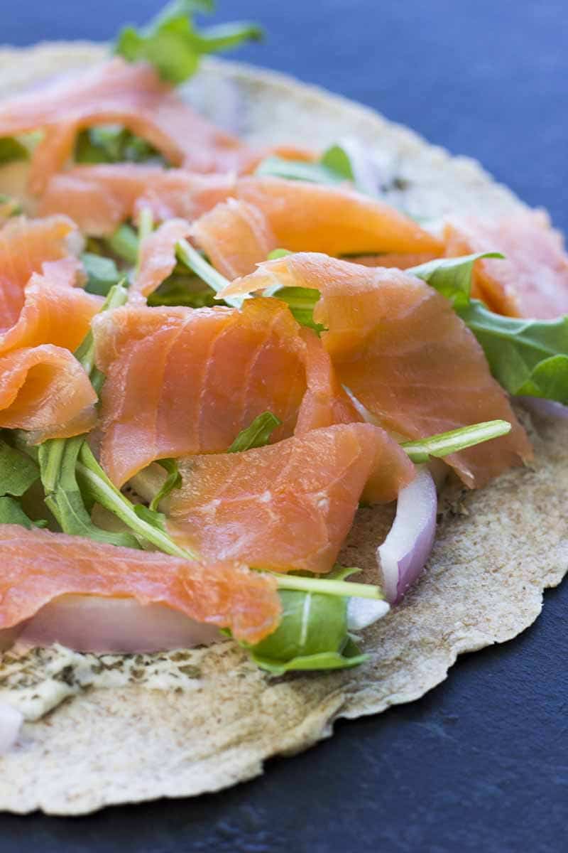 Tortilla with cream cheese, salmon, arugula, and onion on top