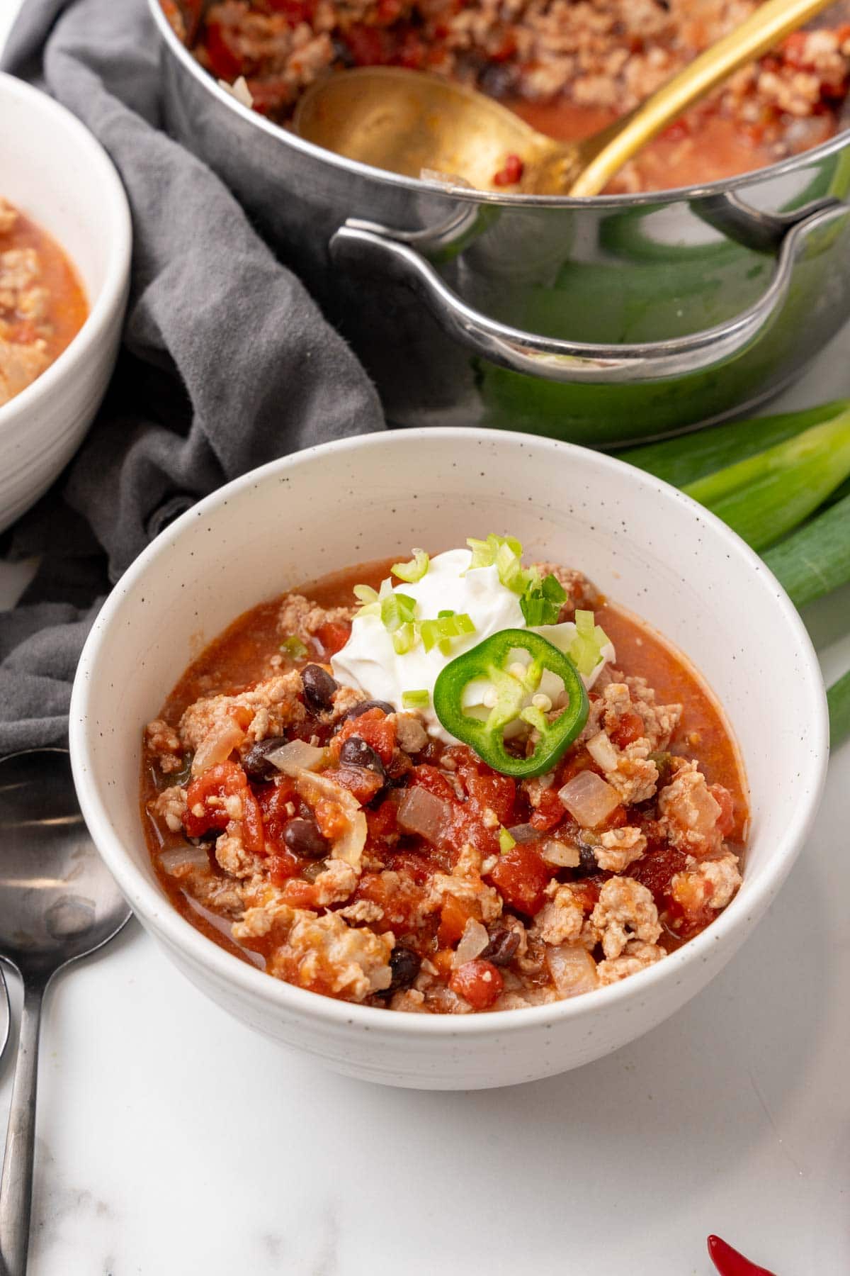 Simple turkey chili in a bowl, topped with sour cream and sliced green onions