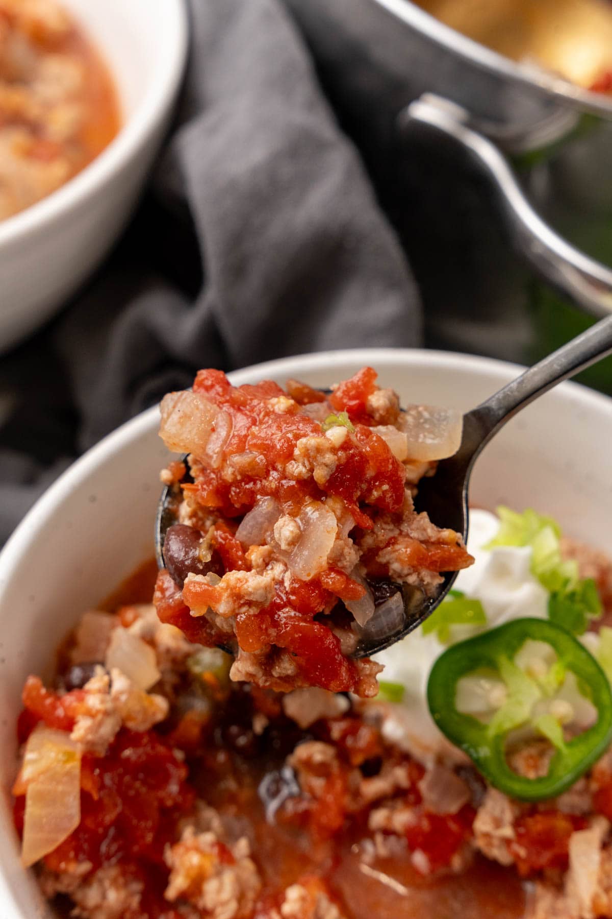 Spoonful of chili held above bowl of chile