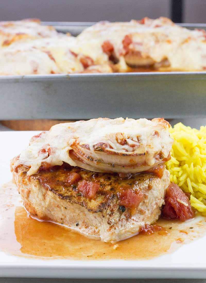 Baked boneless pork chops in tomato sauce plated with rice on the side