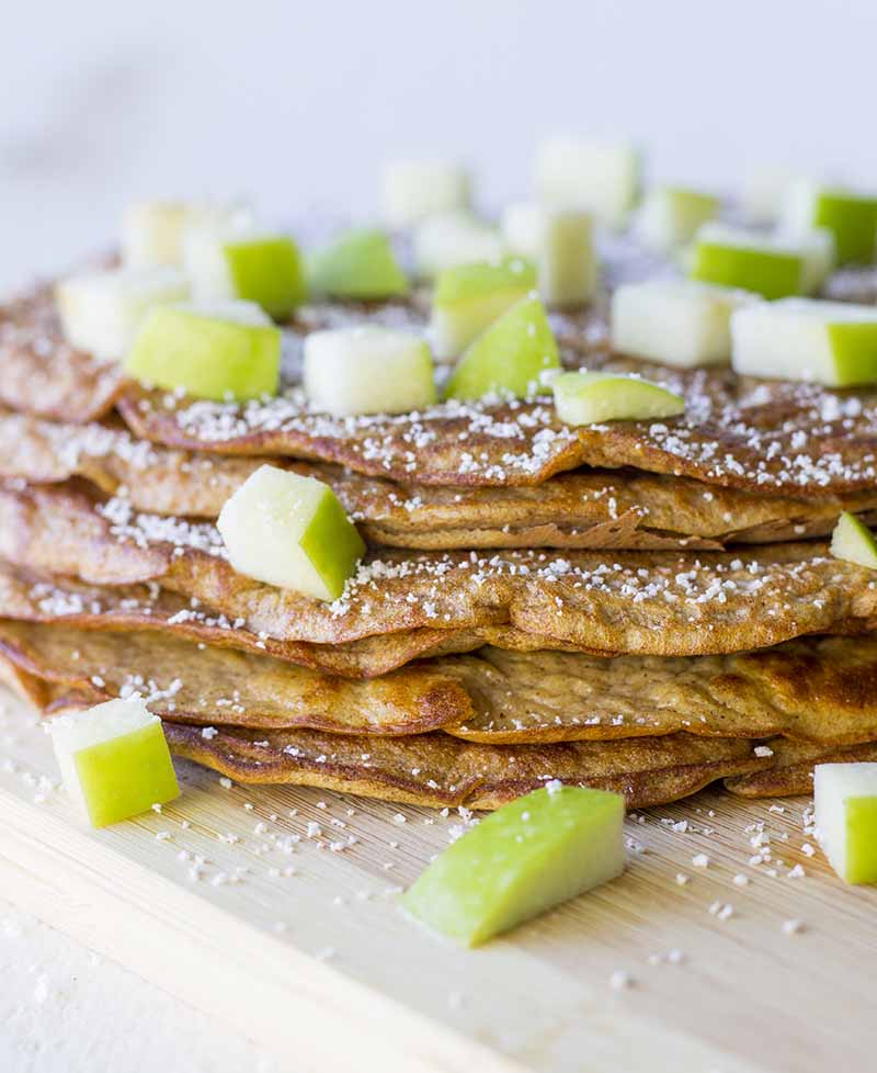 Close-up on a stack of pumpkin pancakes with chopped applies and a sprinkling of Stevia