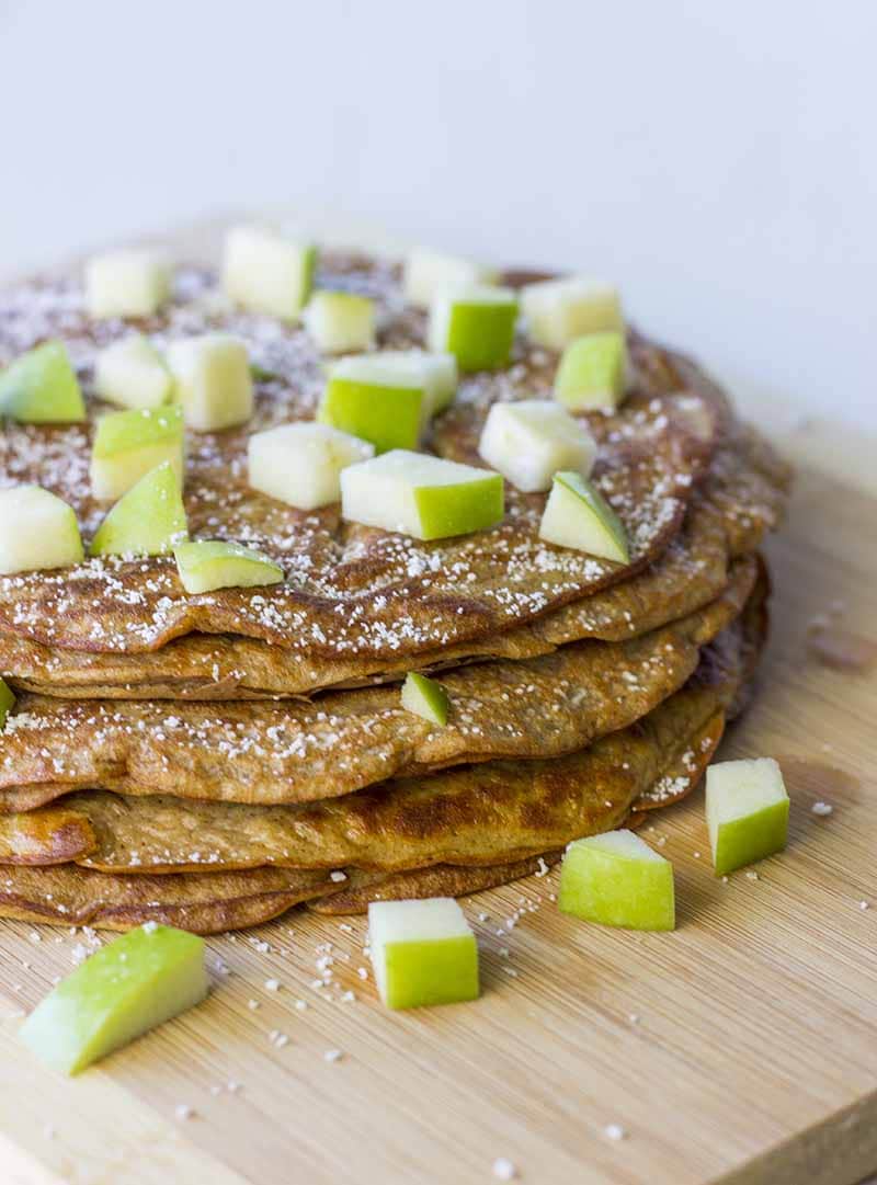 A stack of Healthy Pumpkin Pancakes topped with chopped apples and a sprinkling of Stevia