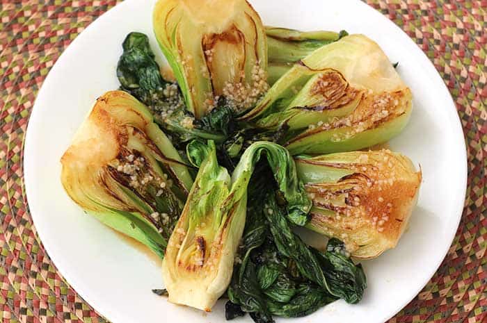 Four heads of Spicy Baby Bok Choy with Warm Ginger Dressing arranged on a white plate