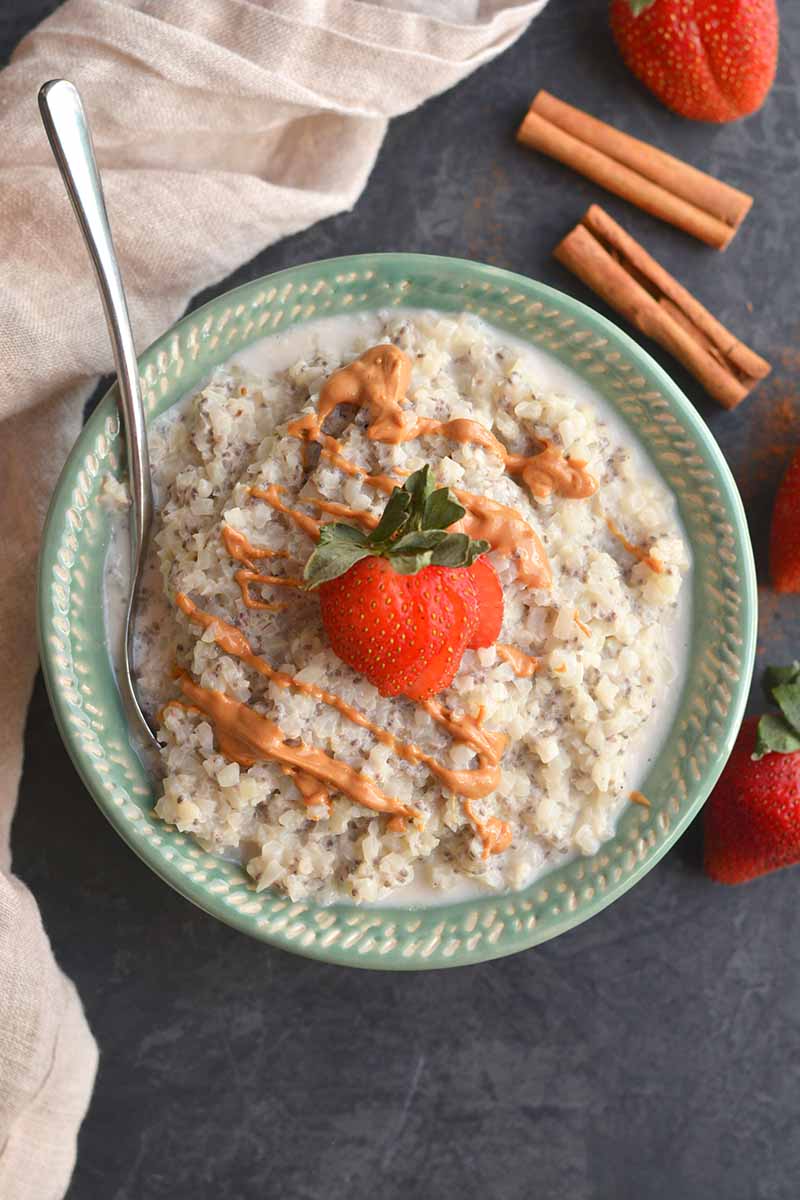 Bowl of cauliflower oatmeal with a strawberry and drizzle of peanut butter on top, as seen from above