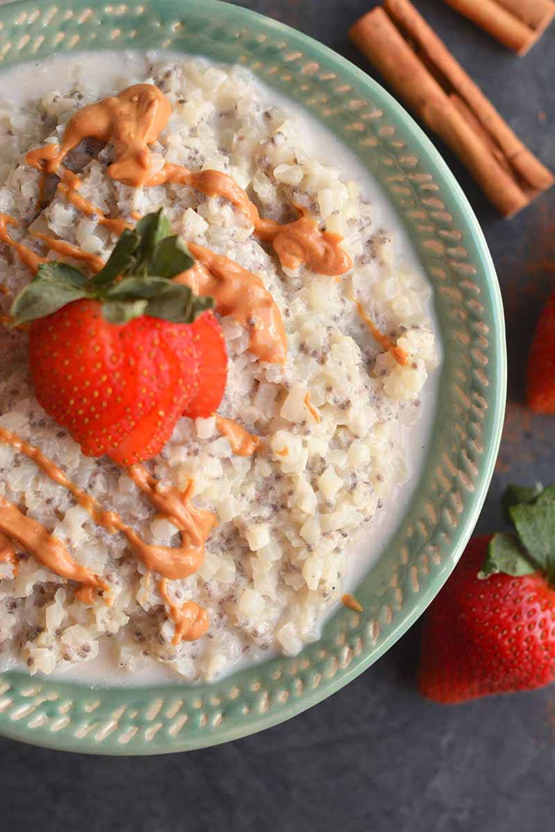 Closeup of oatmeal in a bowl with a sliced strawberry and peanut butter drizzle on top