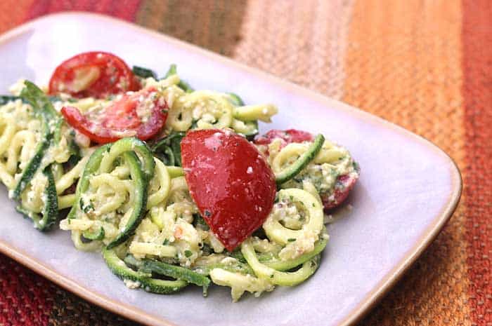 Zucchini Noodles with Lime Pesto garnished with tomatoes on a white plate