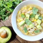 Bowl of slow cooker white chicken chili with chopped avocado and cilantro on top