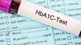 Vial of blood with words "HbA1c Test" resting on a medical chart