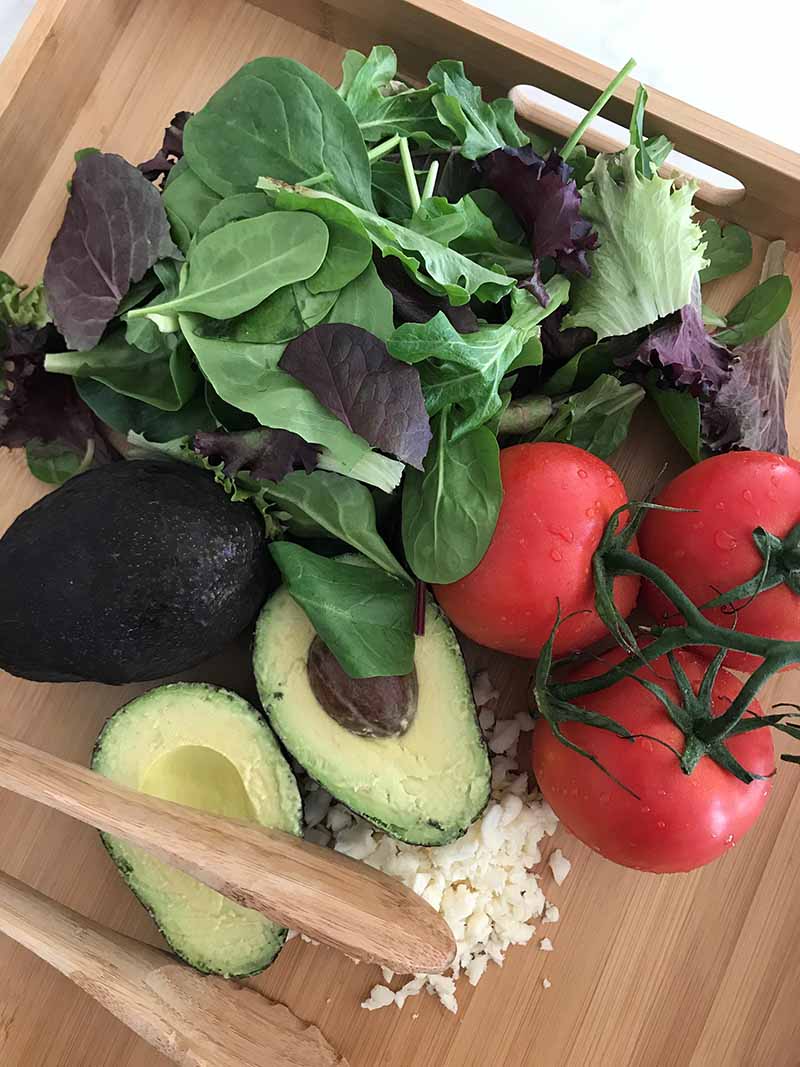 Alle ingrediënten voor de salade op een houten snijplank