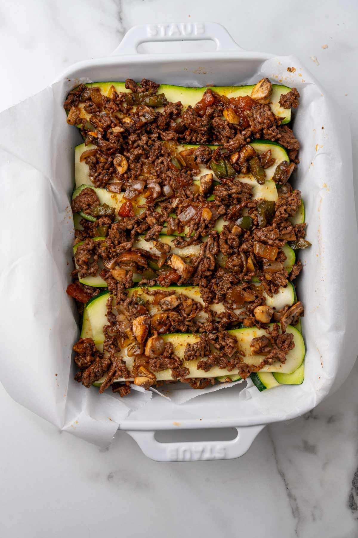 Layers of zucchini and meat sauce in a baking tray