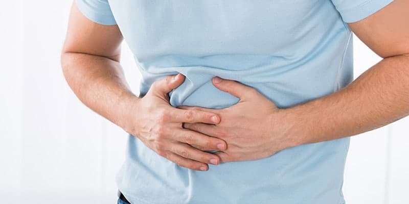 Man grabs stomach with digestive pain