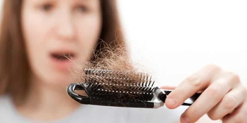 Woman holding a brush containing a large amount of hair