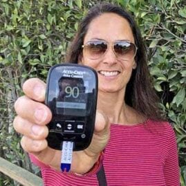 Christel holding a blood glucose monitor showing a 90 mg/dl blood sugar level