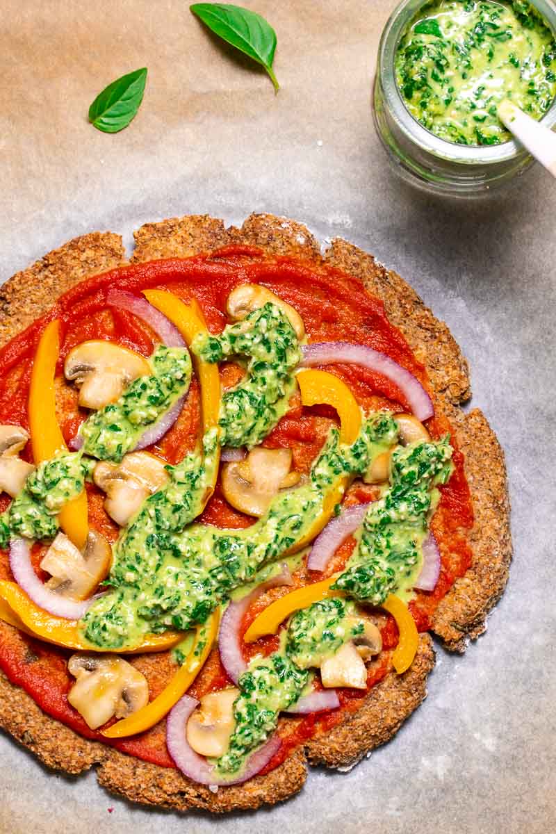 Vegan cauliflower pizza with basil pesto on a baking sheet