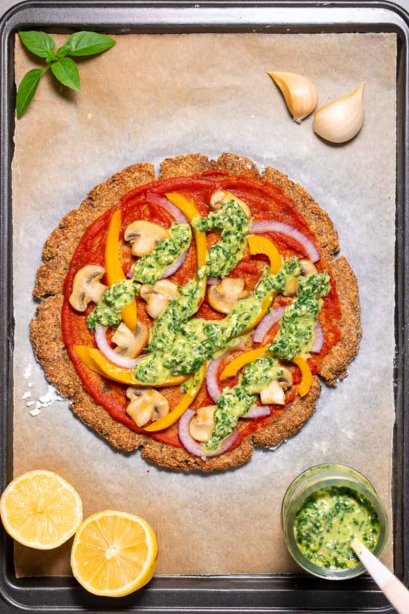 Cauliflower pizza fresh out of the oven and topped with basil pesto