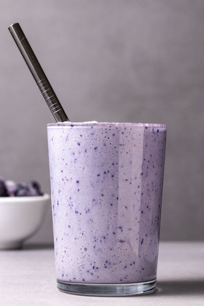 Low-carb vegan blueberry smoothie in tall glass with straw