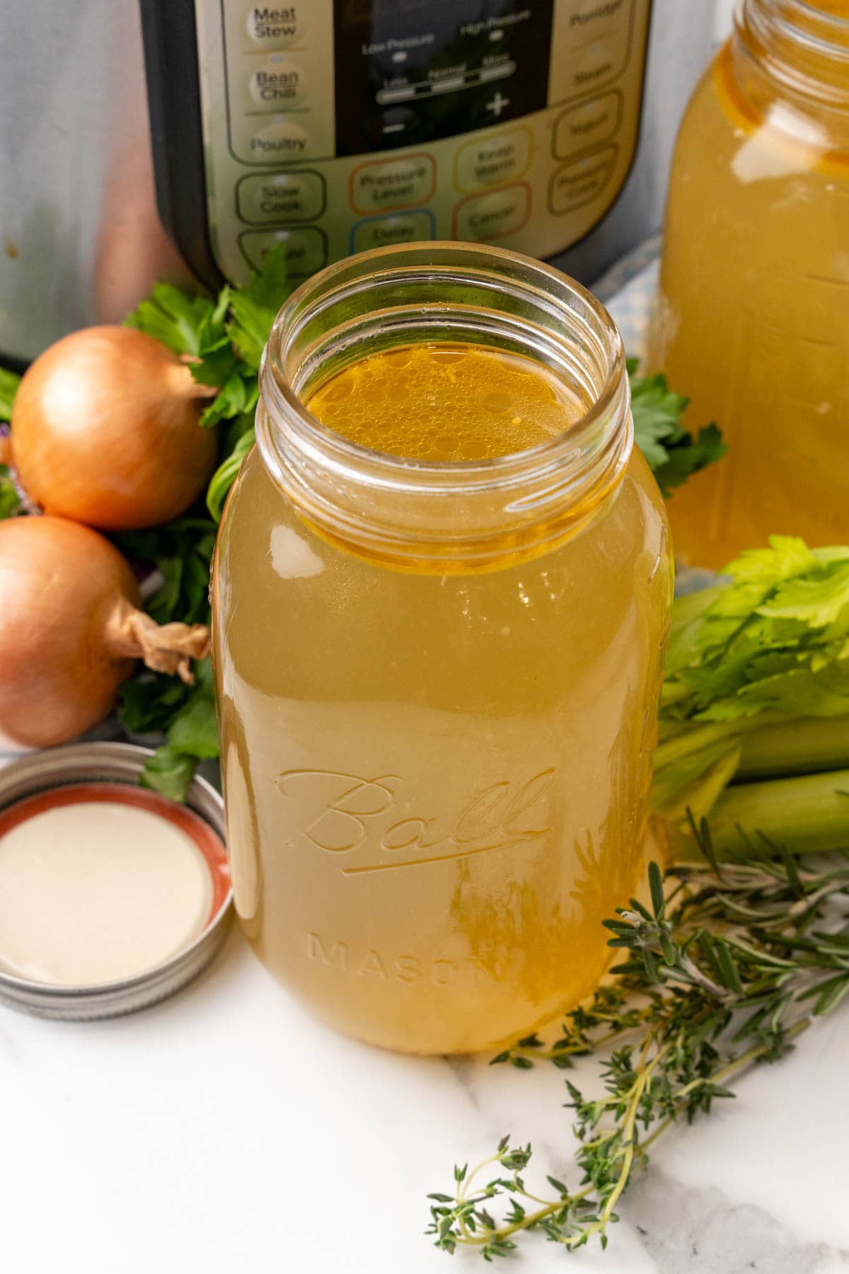 Jar of chicken bone broth in front of an Instant Pot