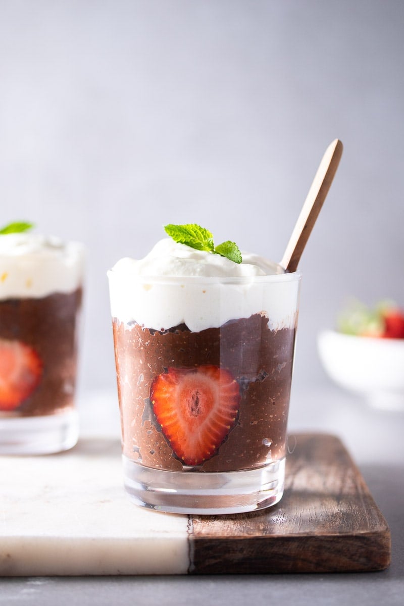 Chocolate Chia Seed Pudding in small glass with strawberry slice, whipped cream, and mint