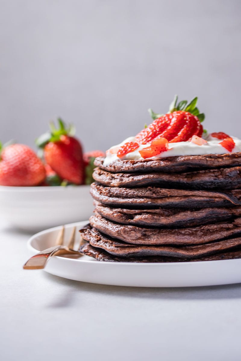 Stack of pancakes with whipped cream and a strawberry